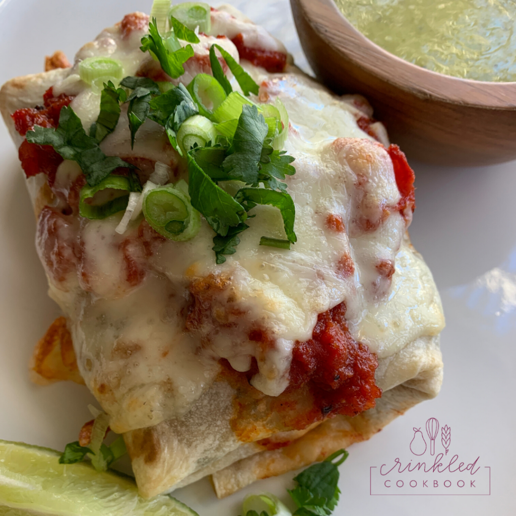 baked burrito on a plate with lime on the side