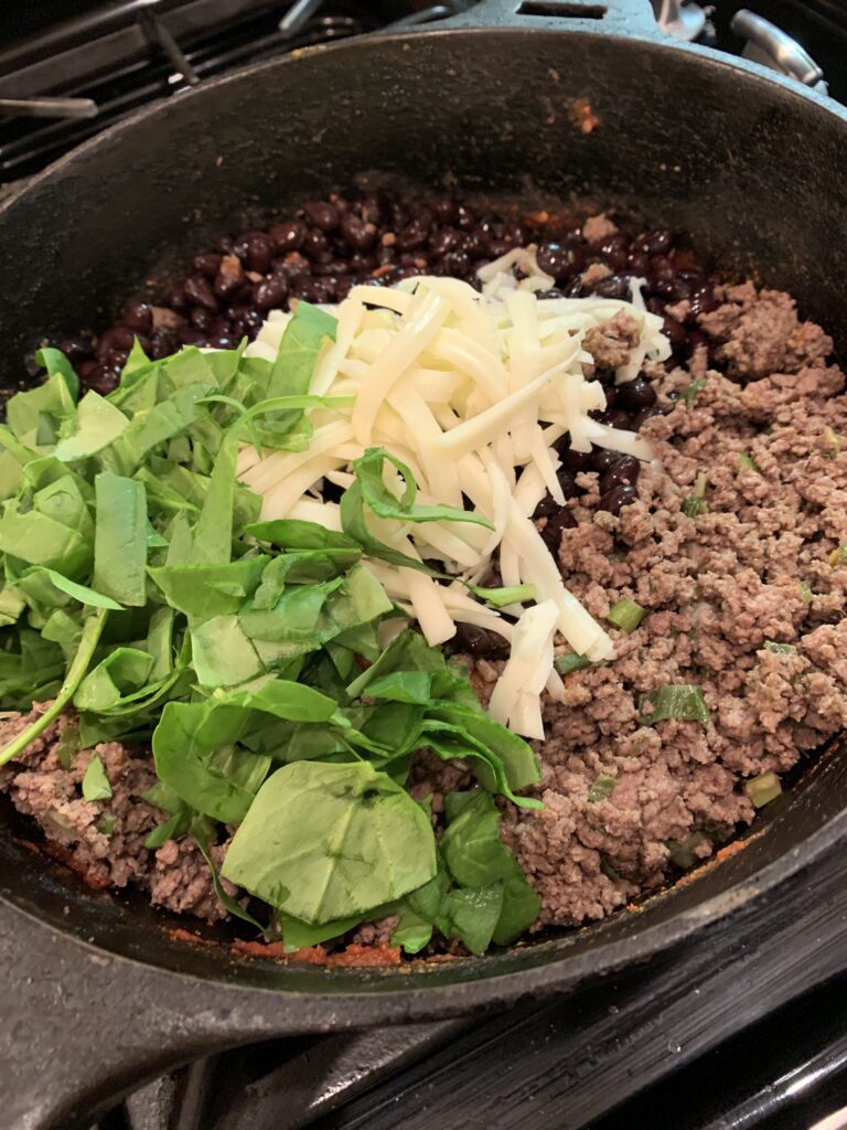 All the ingredients for beef baked burrito filling arranged in a skillet.