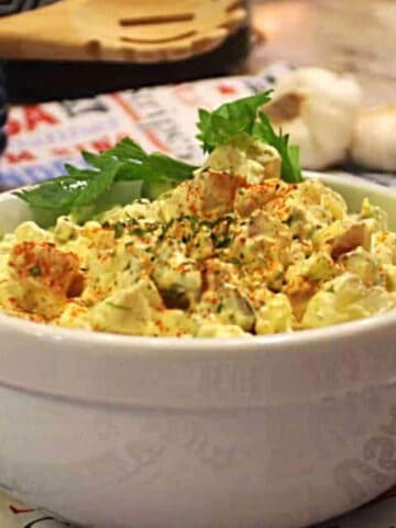 Potato salad in a bowl with fresh parsley leaves on top.