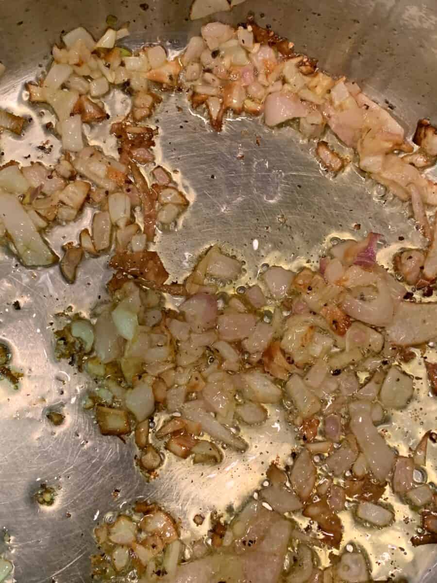 Diced shallots cooking in olive oil in a pan.