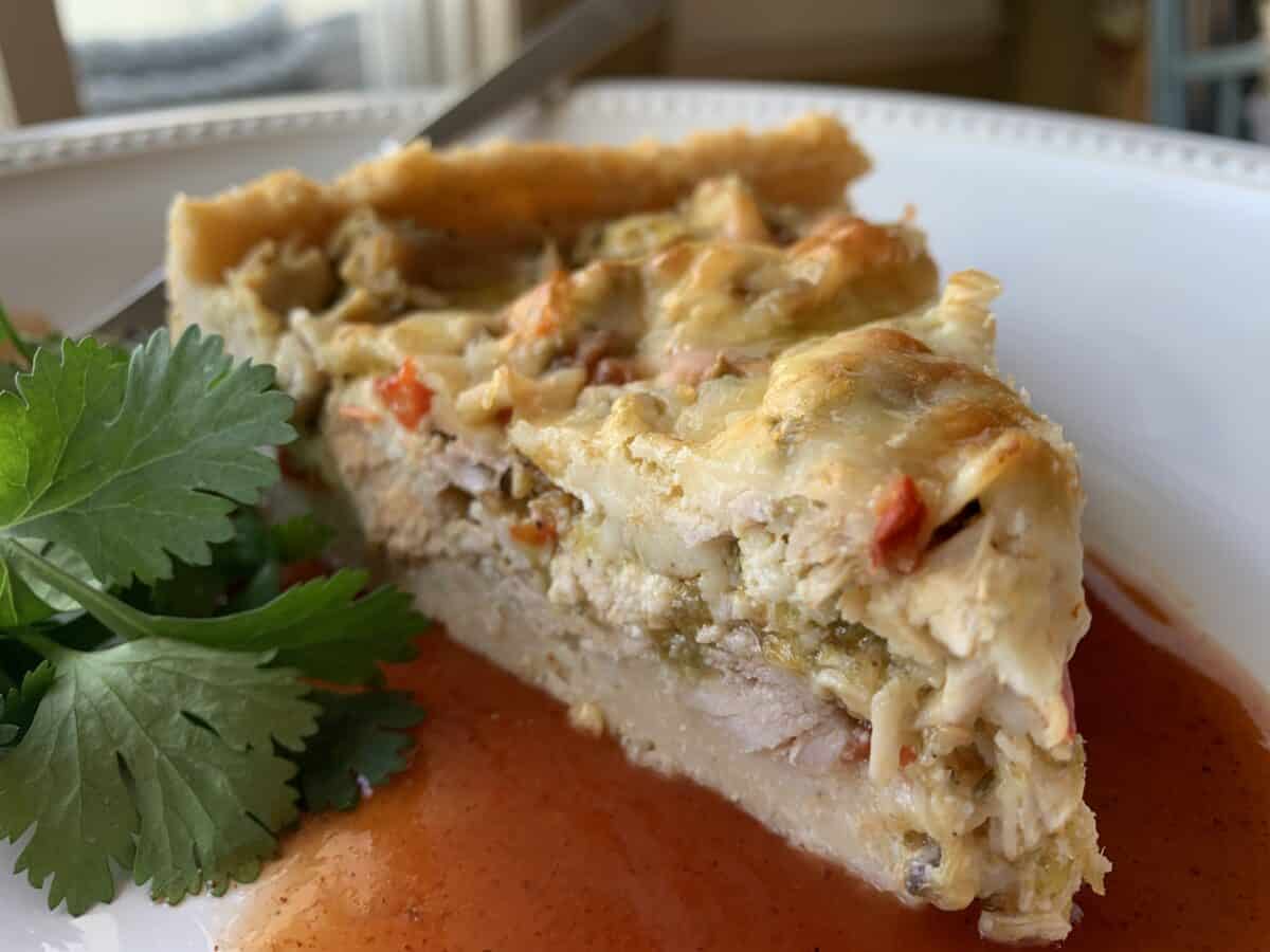 Wedge of tamale casserole on a plate with cilantro garnish.