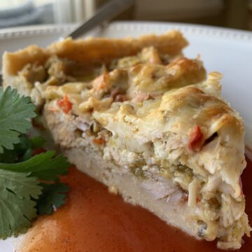 Wedge of tamale casserole on a plate with cilantro garnish.