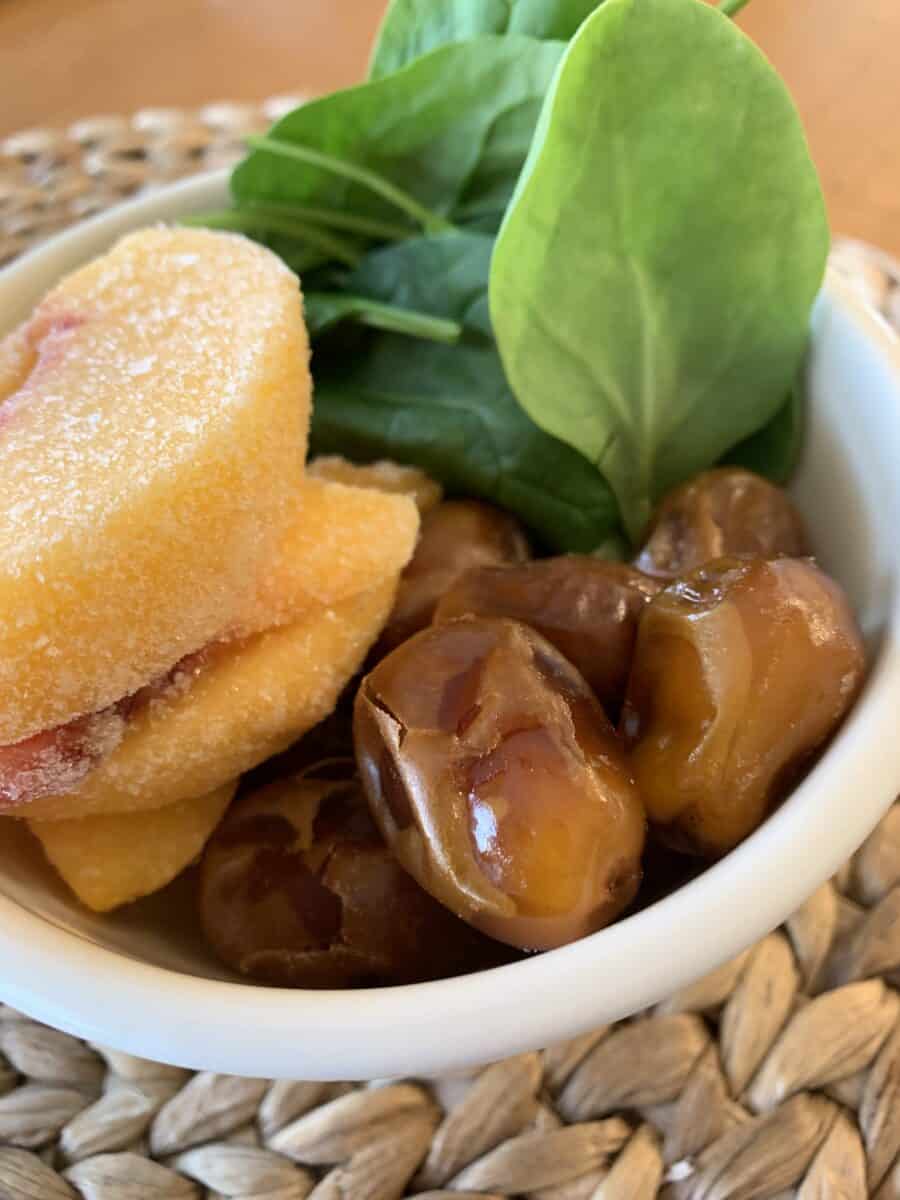 Peaches, dates and spinach in a small bowl. 