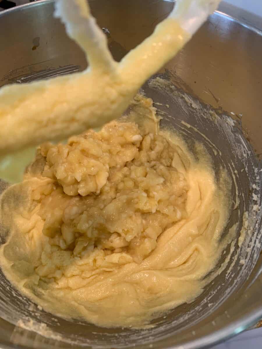 Mashed bananas and other wet ingredients in a mixing bowl.