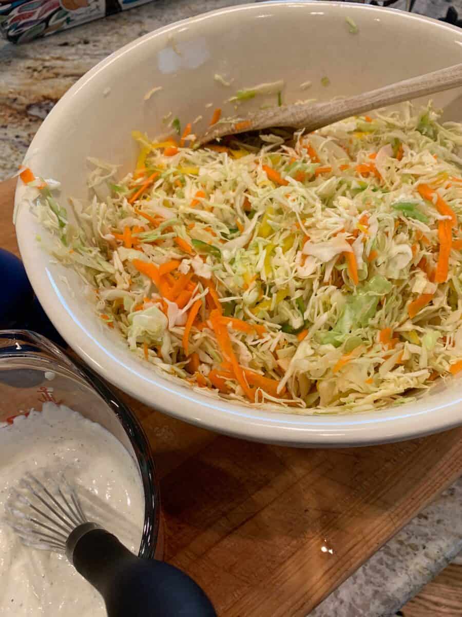 Shredded cole slaw and carrots, dressing in a small bowl on the side.