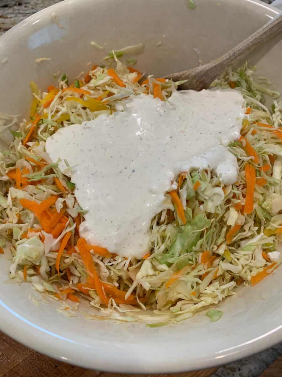 Shredded cole slaw and carrots with dressing on top.