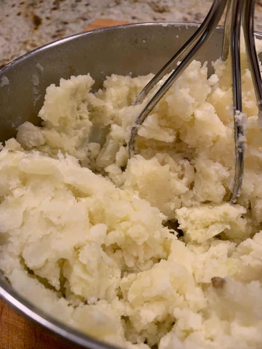 Potatoes in a metal bowl, mashed.