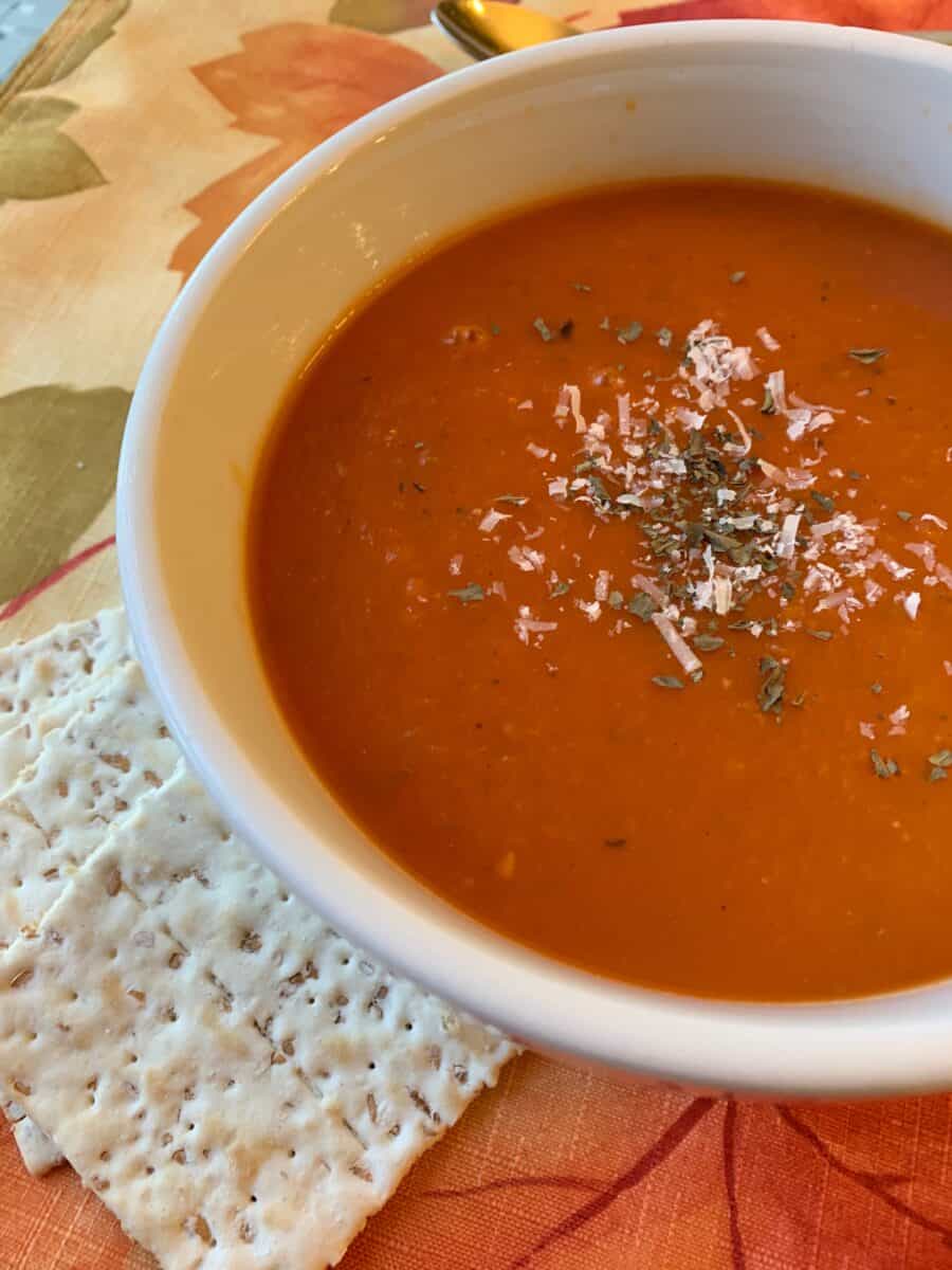 Tomato Basil Soup in a bowl with crackers on the side.