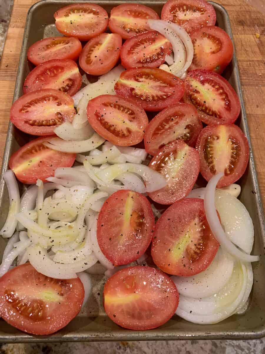 Tomatoes, garlic and onions chopped and arranged on a baking sheet. 