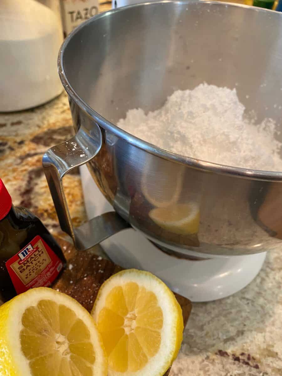 Sliced lemon next to a mixer full of powdered sugar.