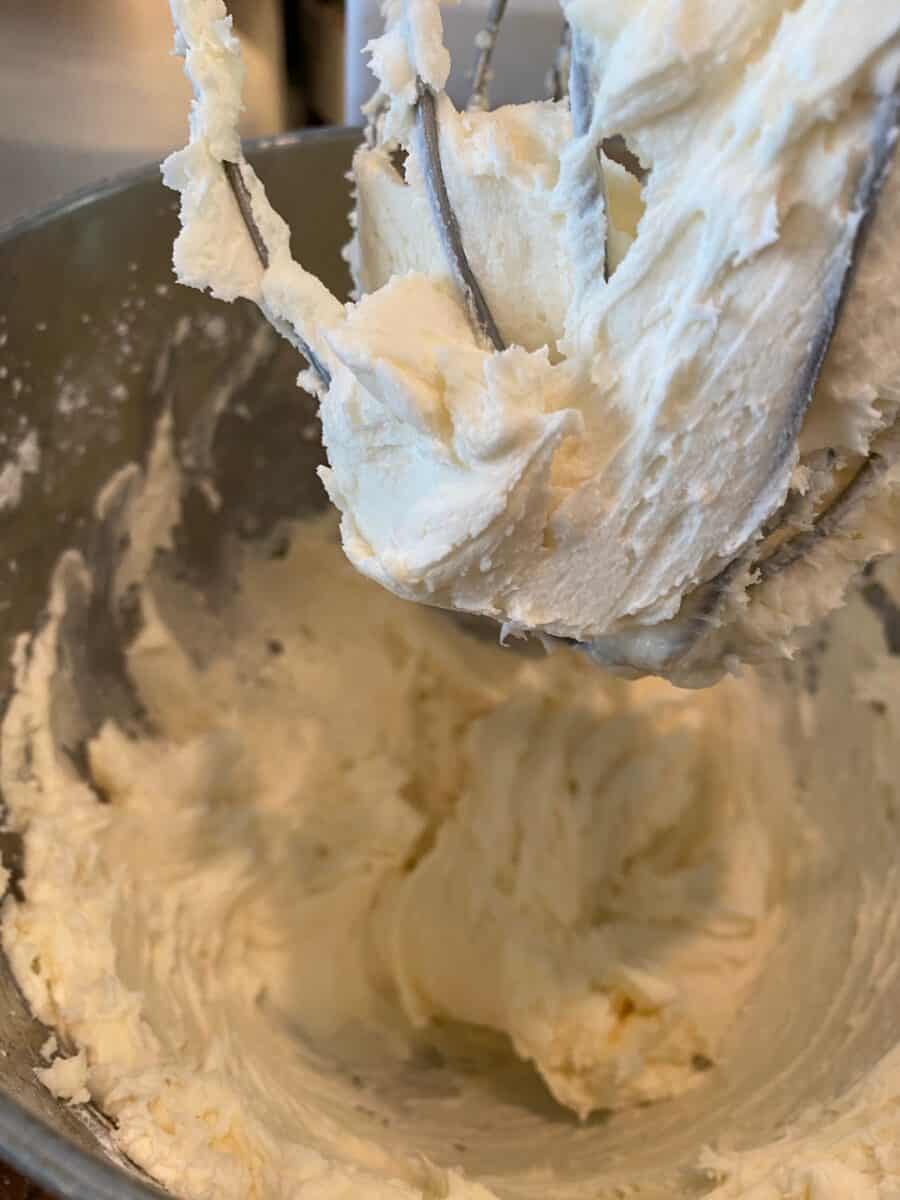 Buttercream frosting in the mixing bowl and on a whisk. 