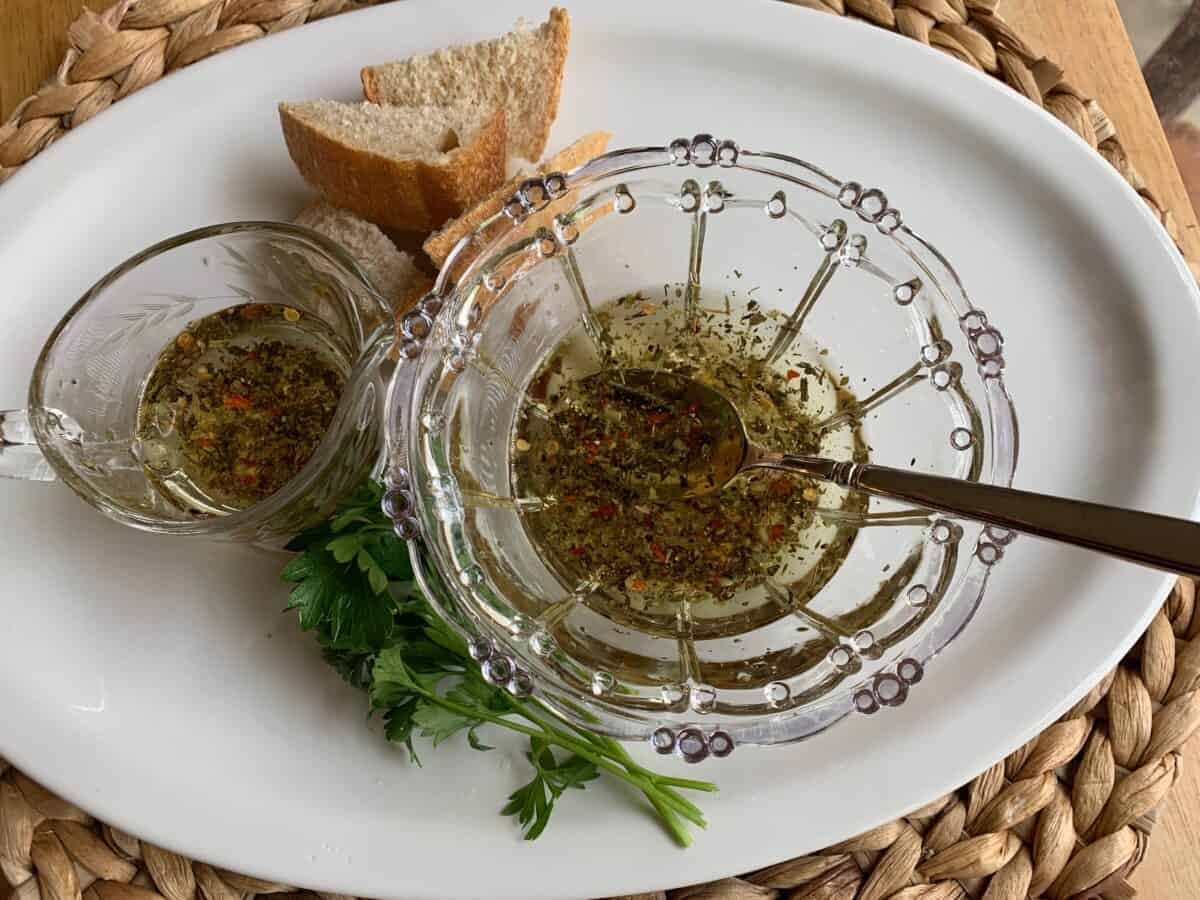 Dipping oil in a glass bowl on a plate with a wedge of bread. 