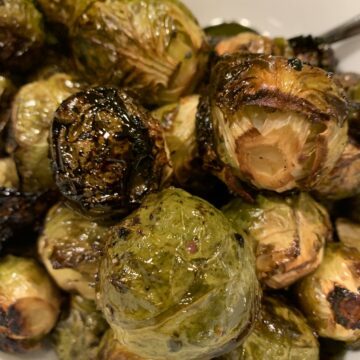 Maple and balsamic drenched Brussel sprouts mounded on a serving plate.