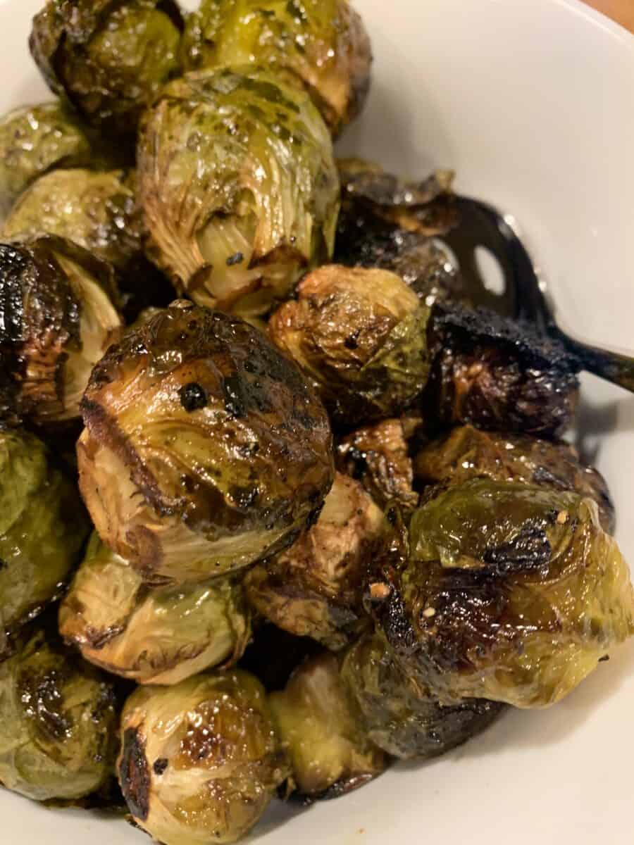 Whole, glazed Brussels sprouts on a serving bowl after roasting