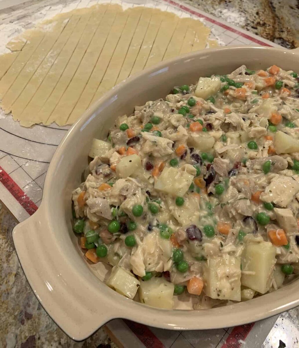 Turkey pot pie in a dish placed next to strips of raw crust.