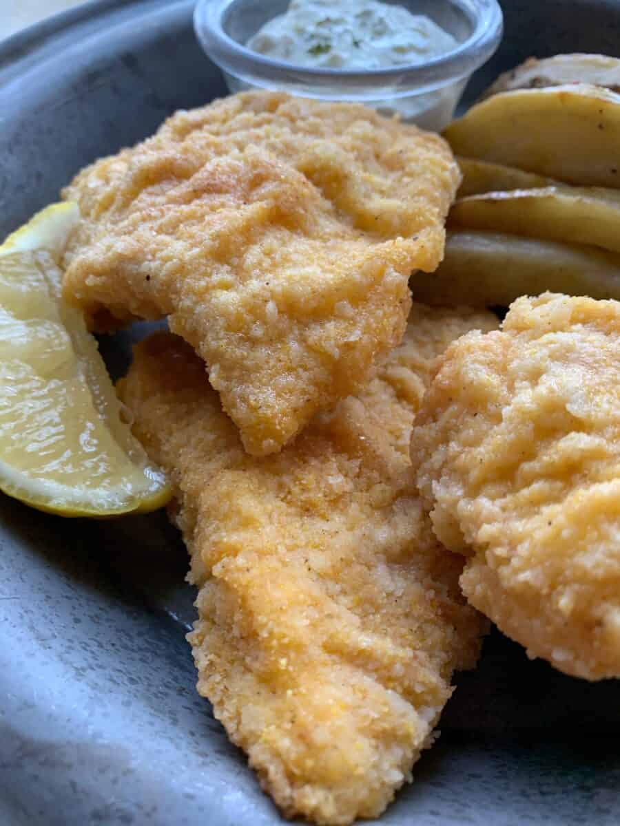 Three pieces of fried cod on a metal plate.