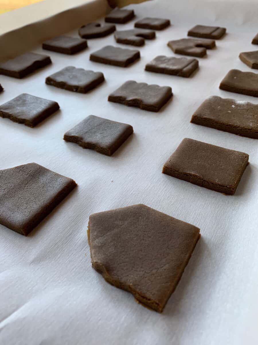 Portions of the mini-gingerbread house on a baking sheet, ready to bake. 