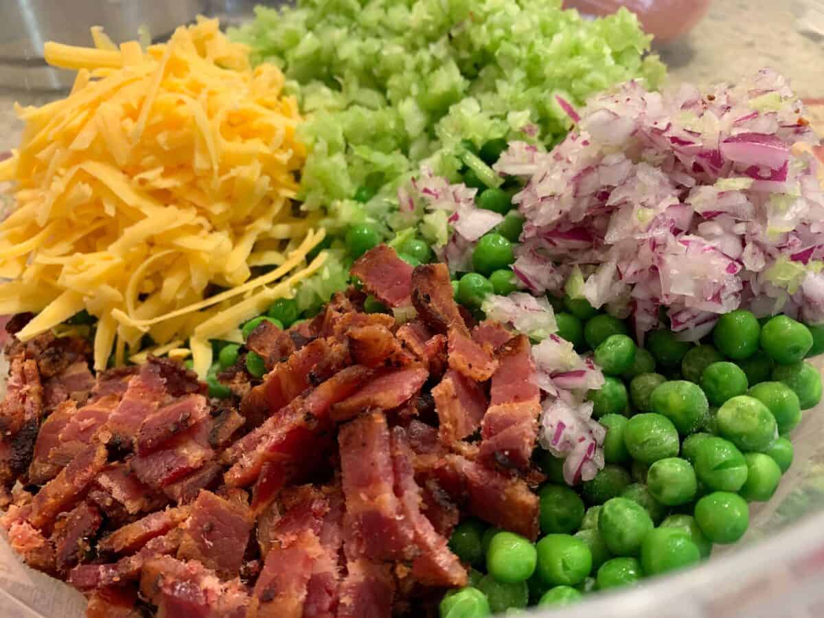 Pea salad ingredients: bacon, cheese, celery, bacon and red onions. 