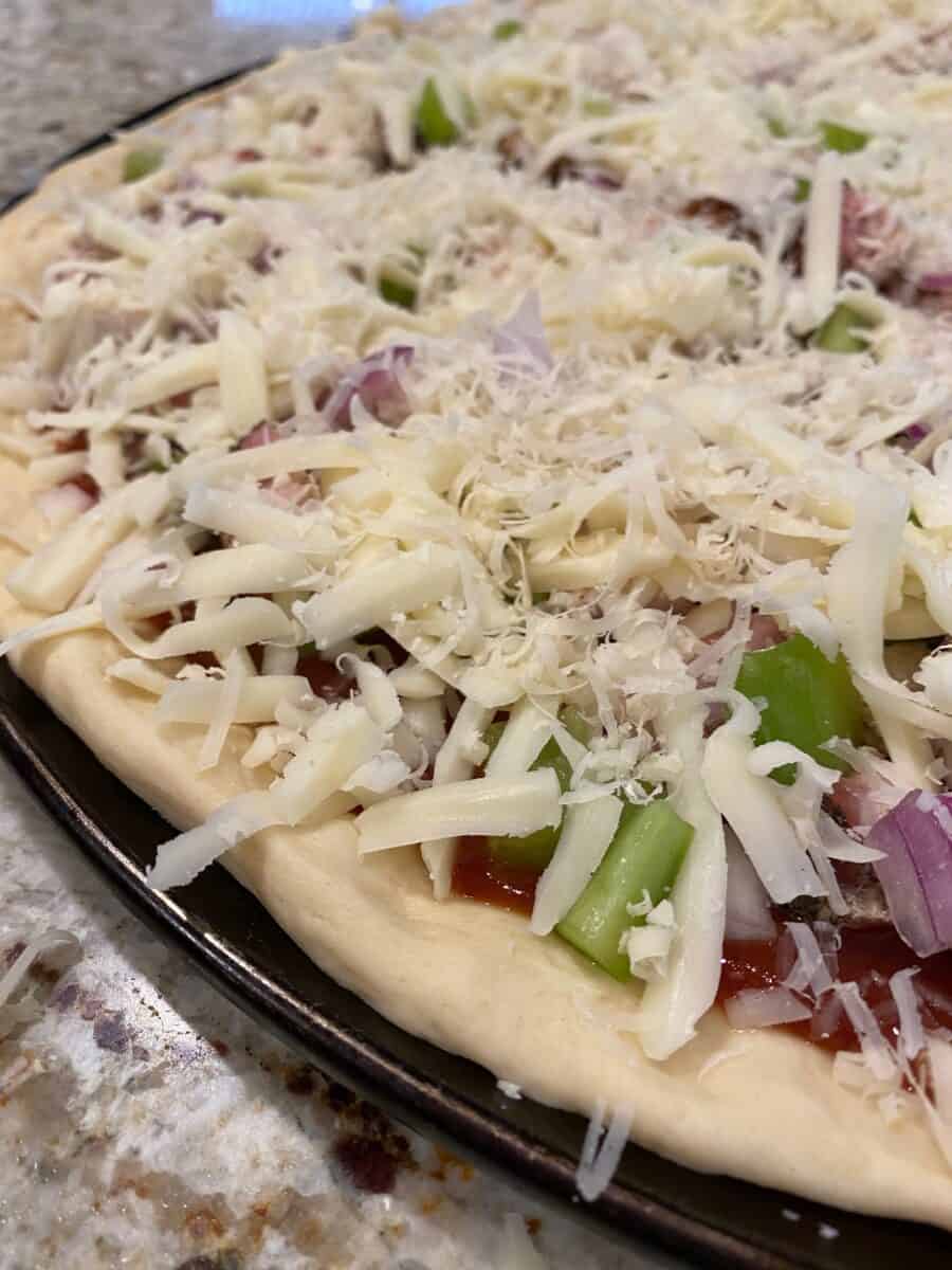 Unbaked pizza with toppings added. 