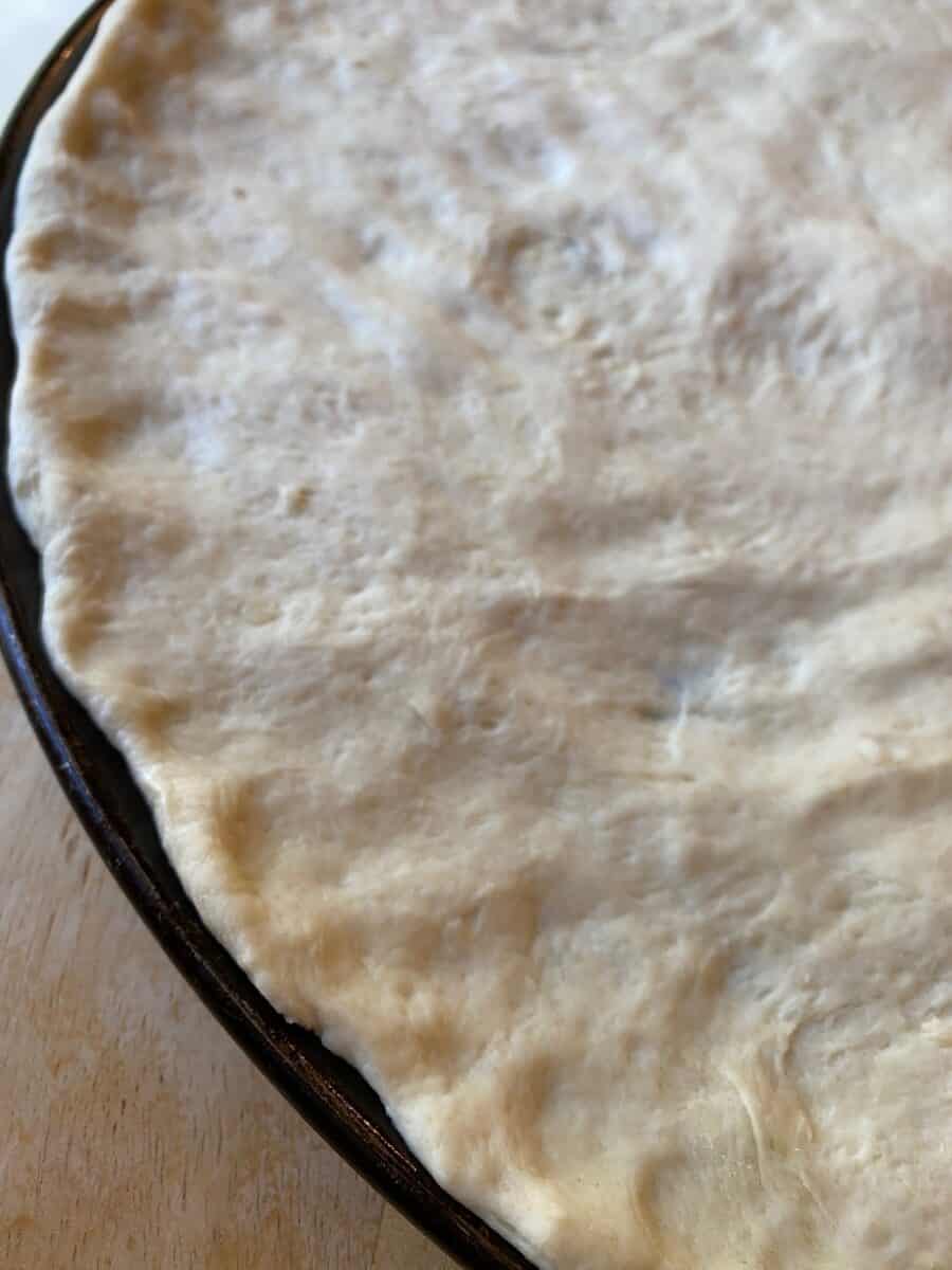 Unbaked pizza dough on a pizza pan. 