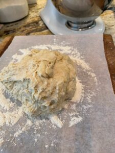 Pizza dough on a floured piece of parchment paper. 