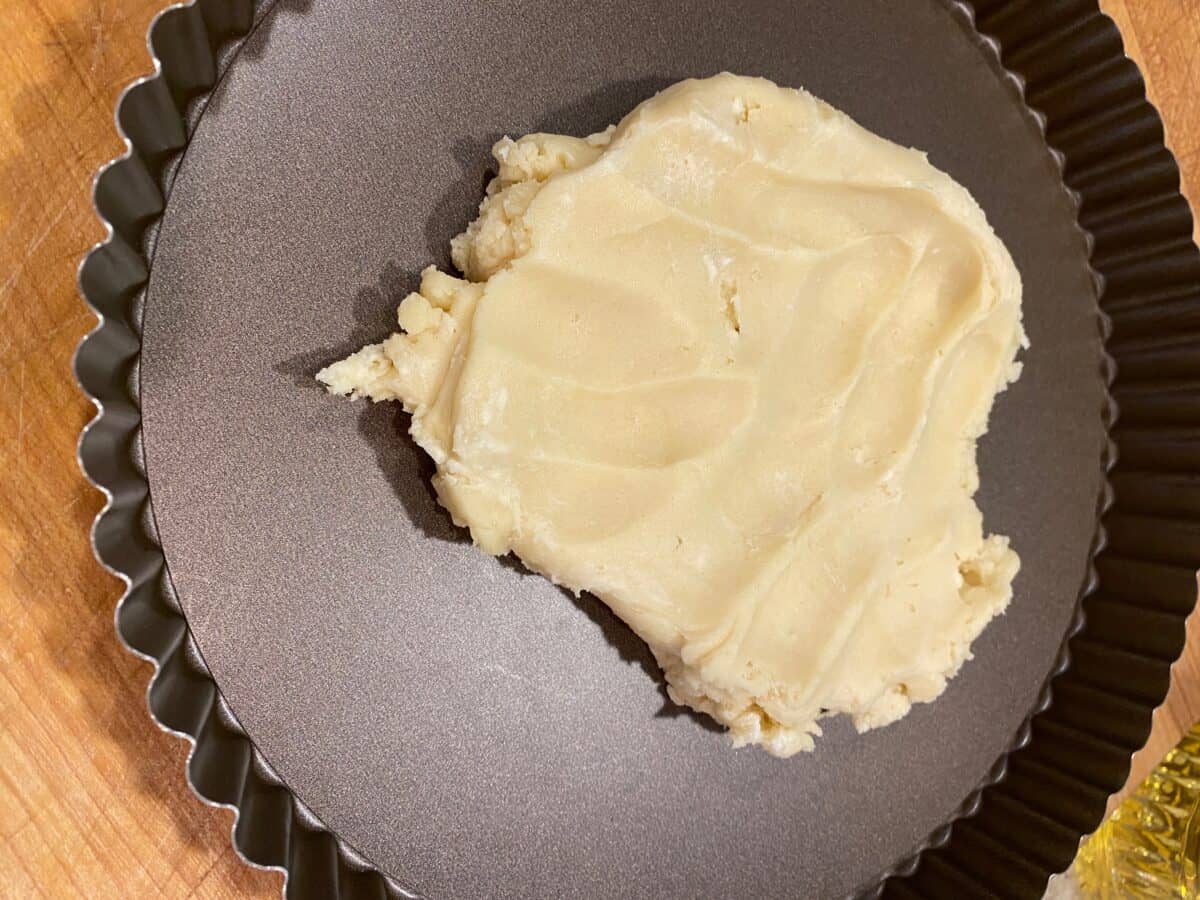 Unbaked fruit tart crust in a mound on a tart pan. 