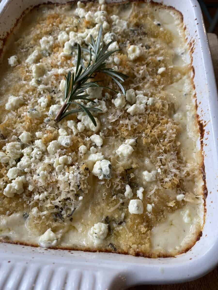 Baked blue cheese and rosemary scalloped potatoes with a sprig of rosemary on top. 