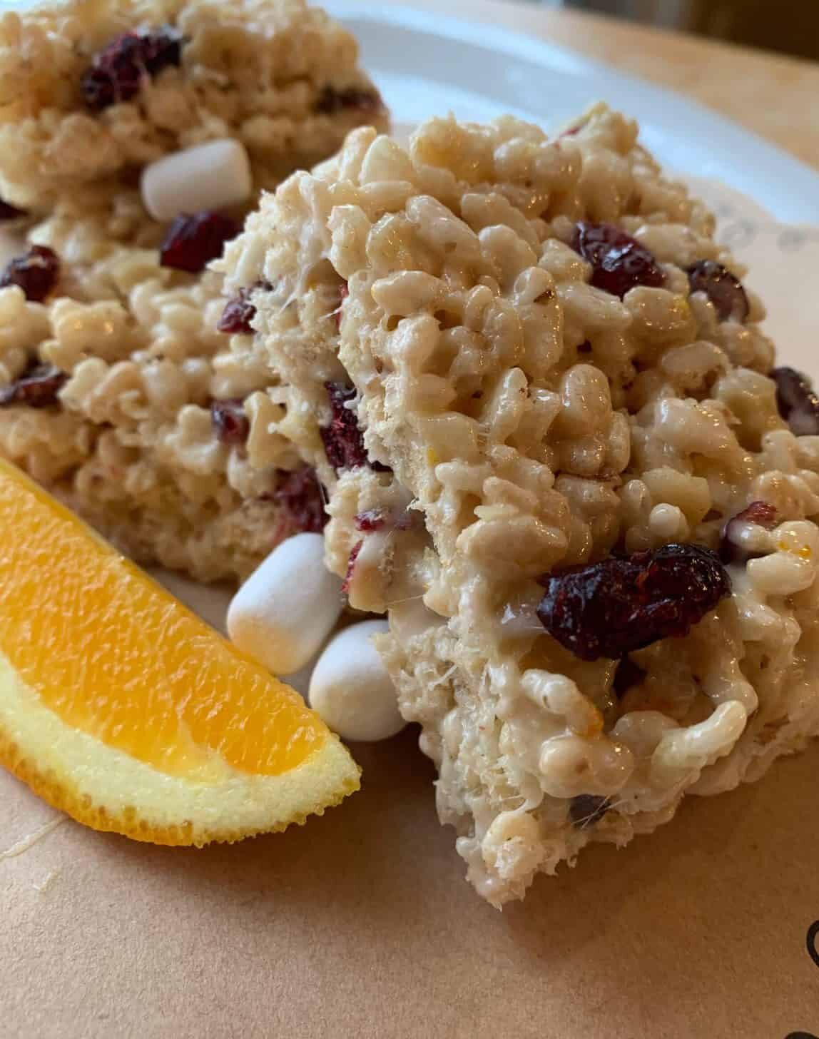 Rice Krispie treats stacked with a wedge of orange on the side.