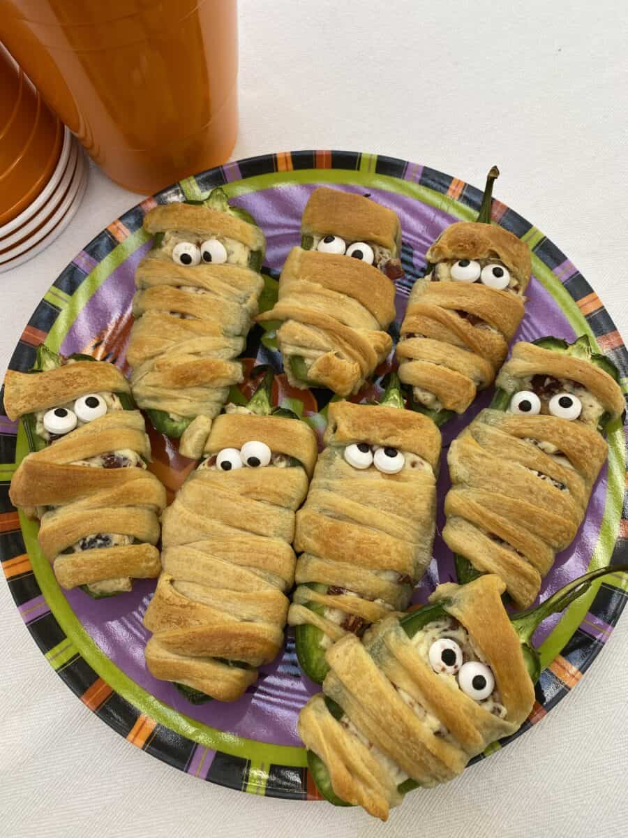 A plate with eight wrapped jalapeño bacon mummies wrapped in dough.