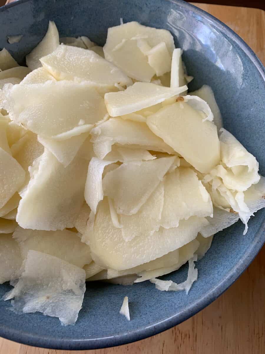 Sliced, raw potatoes in a bowl. 