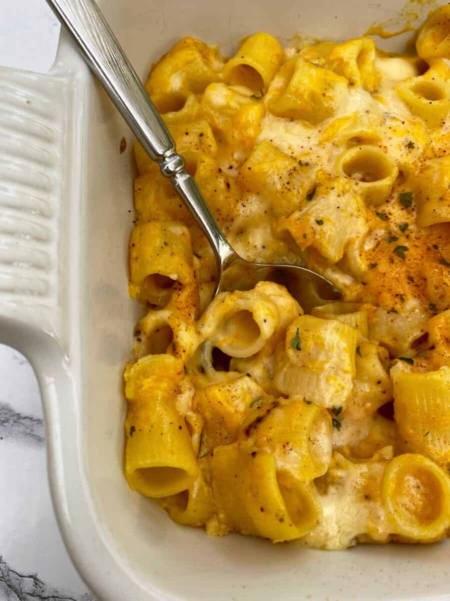 Mac and cheese in a dish with a serving spoon.