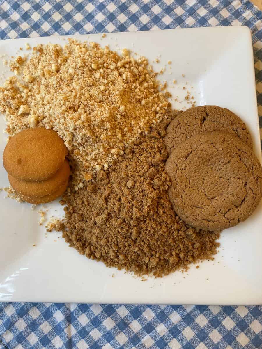 Gingersnaps and vanilla wafers placed next to crushed cookies and on a dish.