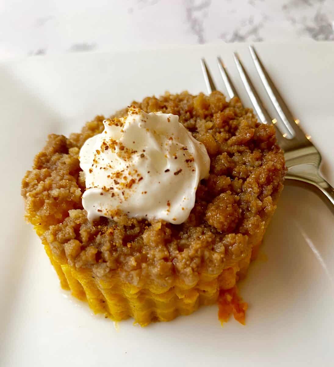 Dessert portion of cookie crumb casserole on a plate with whipped cream on top.