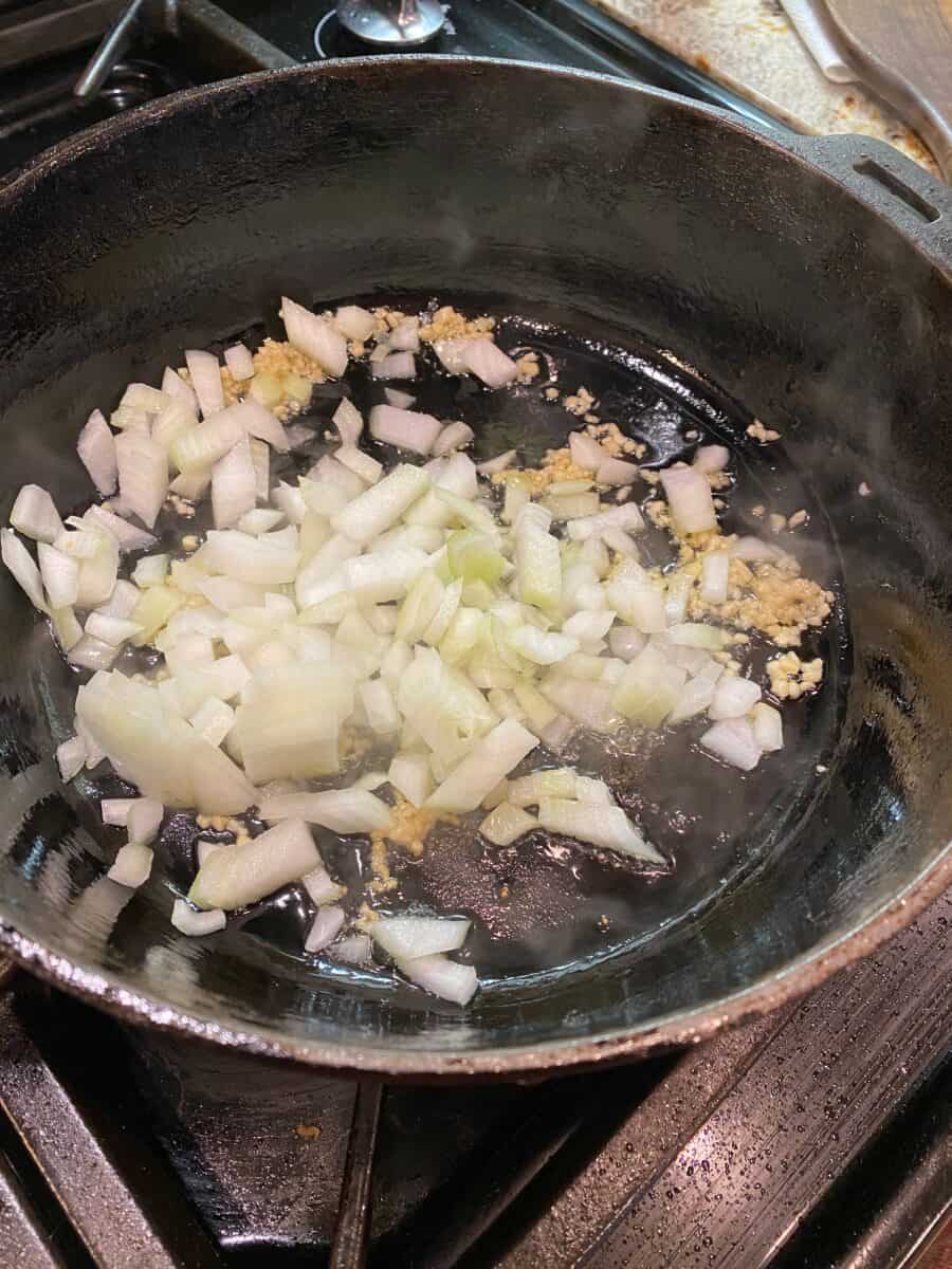 Onions and garlic in a cast iron skillet on the stove.