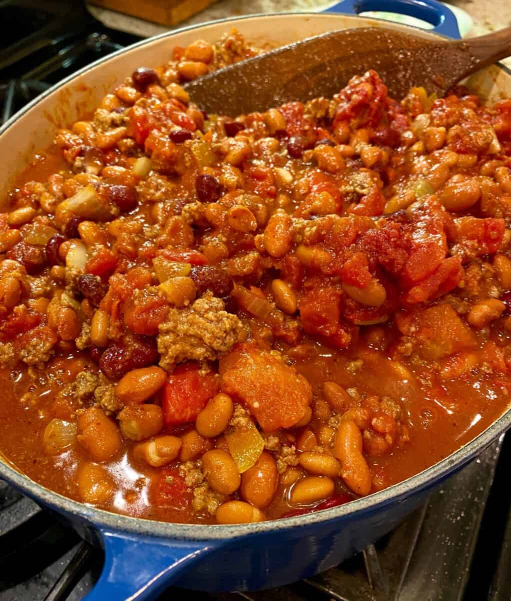 A large stockpot on the stove full of chili. 