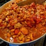 A large stockpot on the stove full of chili.