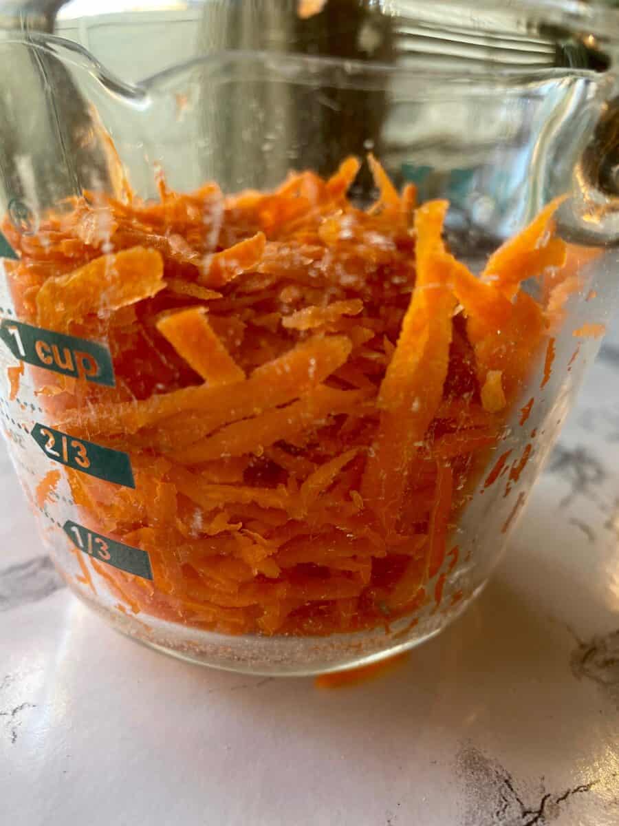 Grated carrots in a one-cup measuring bowl.