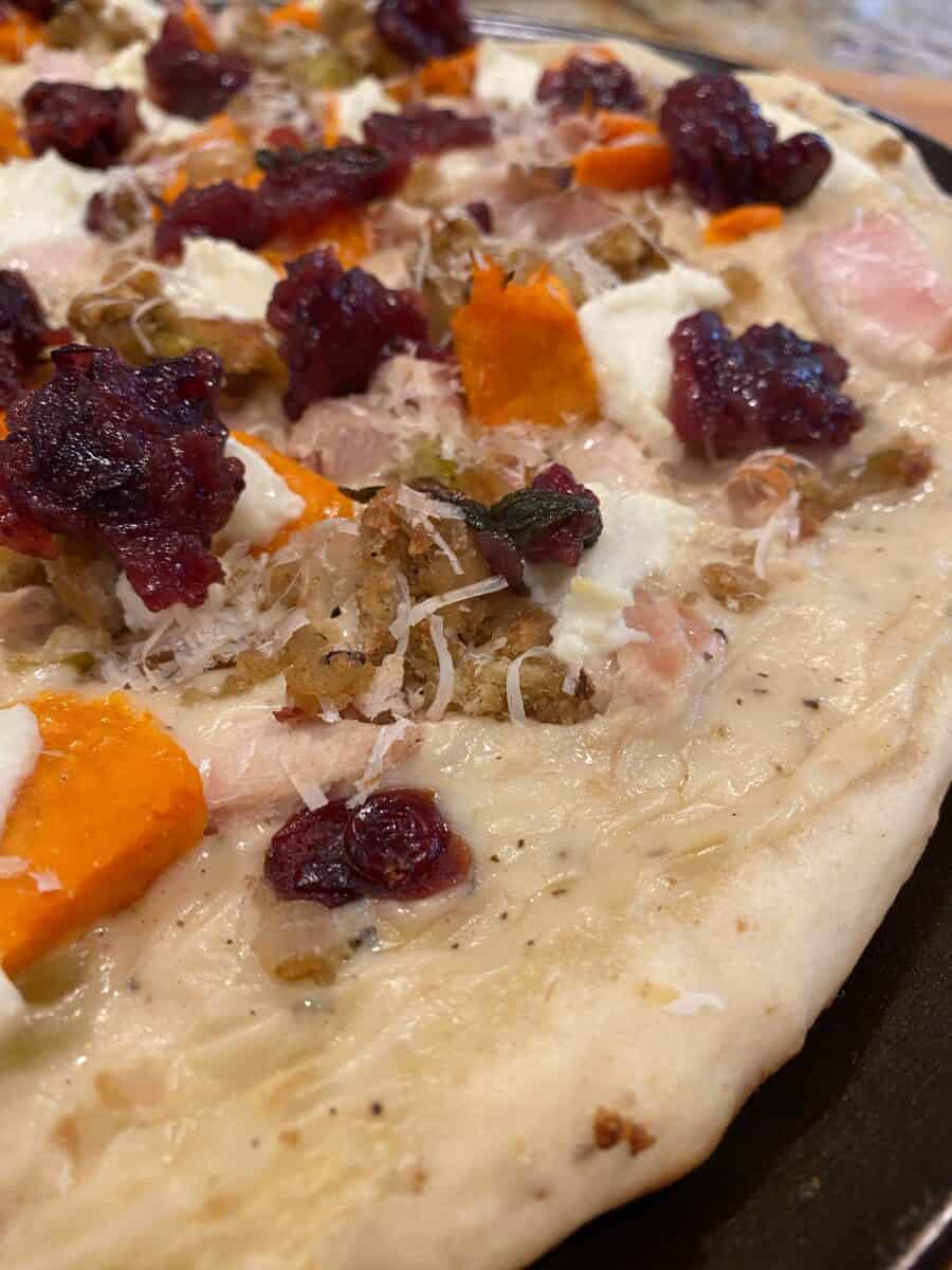 Pizza crust topped with turkey, sweet potatoes, stuffing and cranberries.