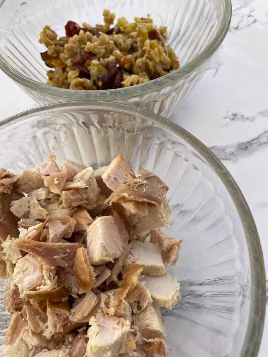 Leftover turkey and stuffing in two separate glass bowls.