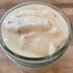 White pizza sauce in a small glass jar.