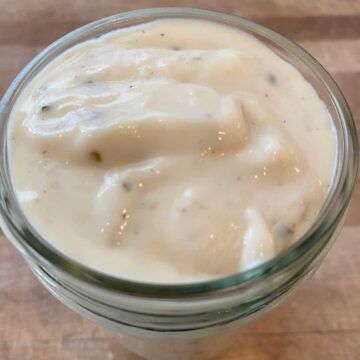 White pizza sauce in a small glass jar.