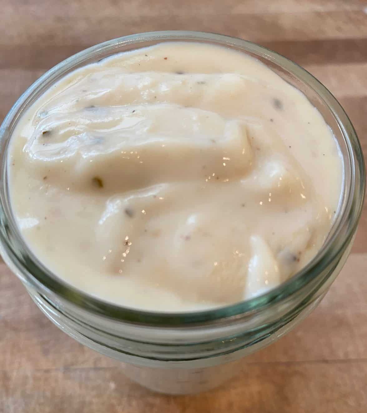 White pizza sauce in a small glass jar.