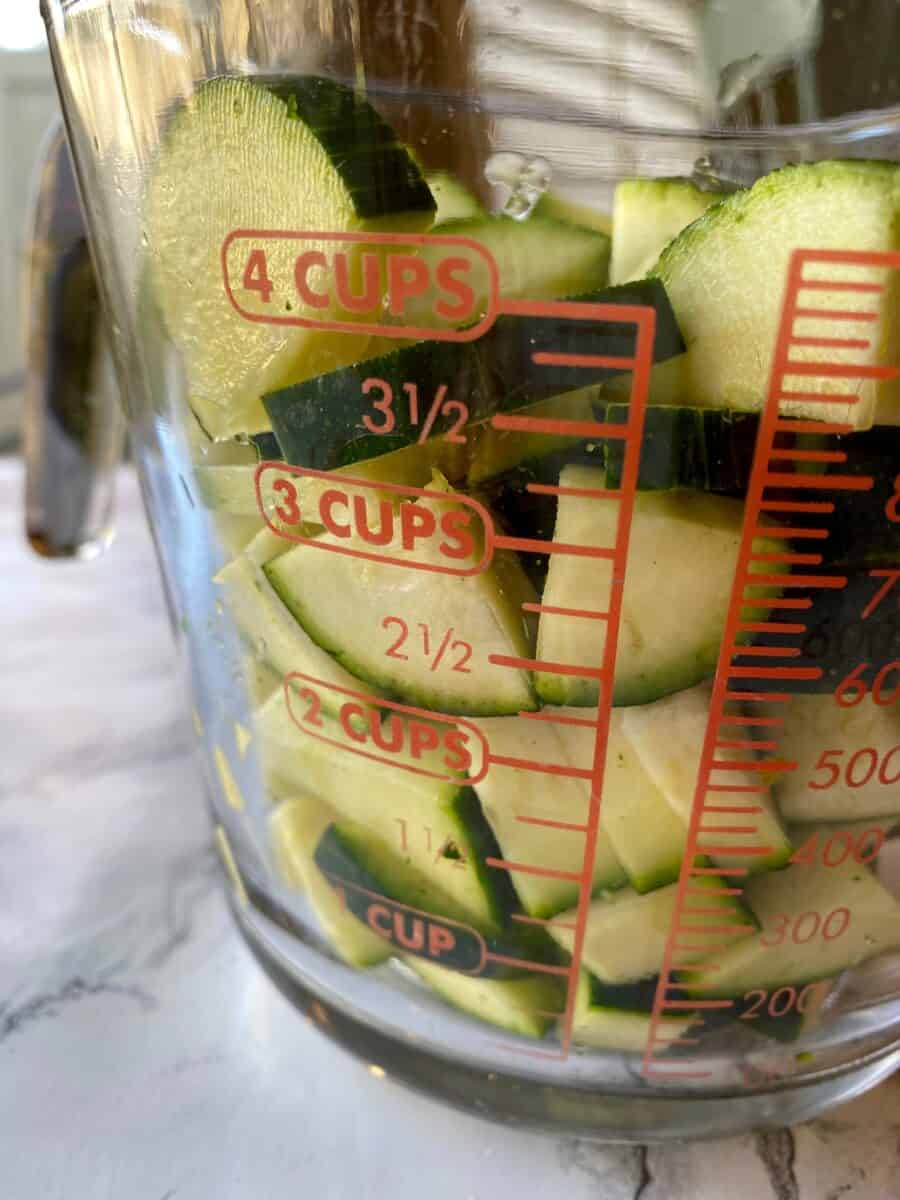 Diced zucchini in a 4-cup glass measuring cup.