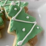 Sugar cookies shaped like Christmas trees on a plate.