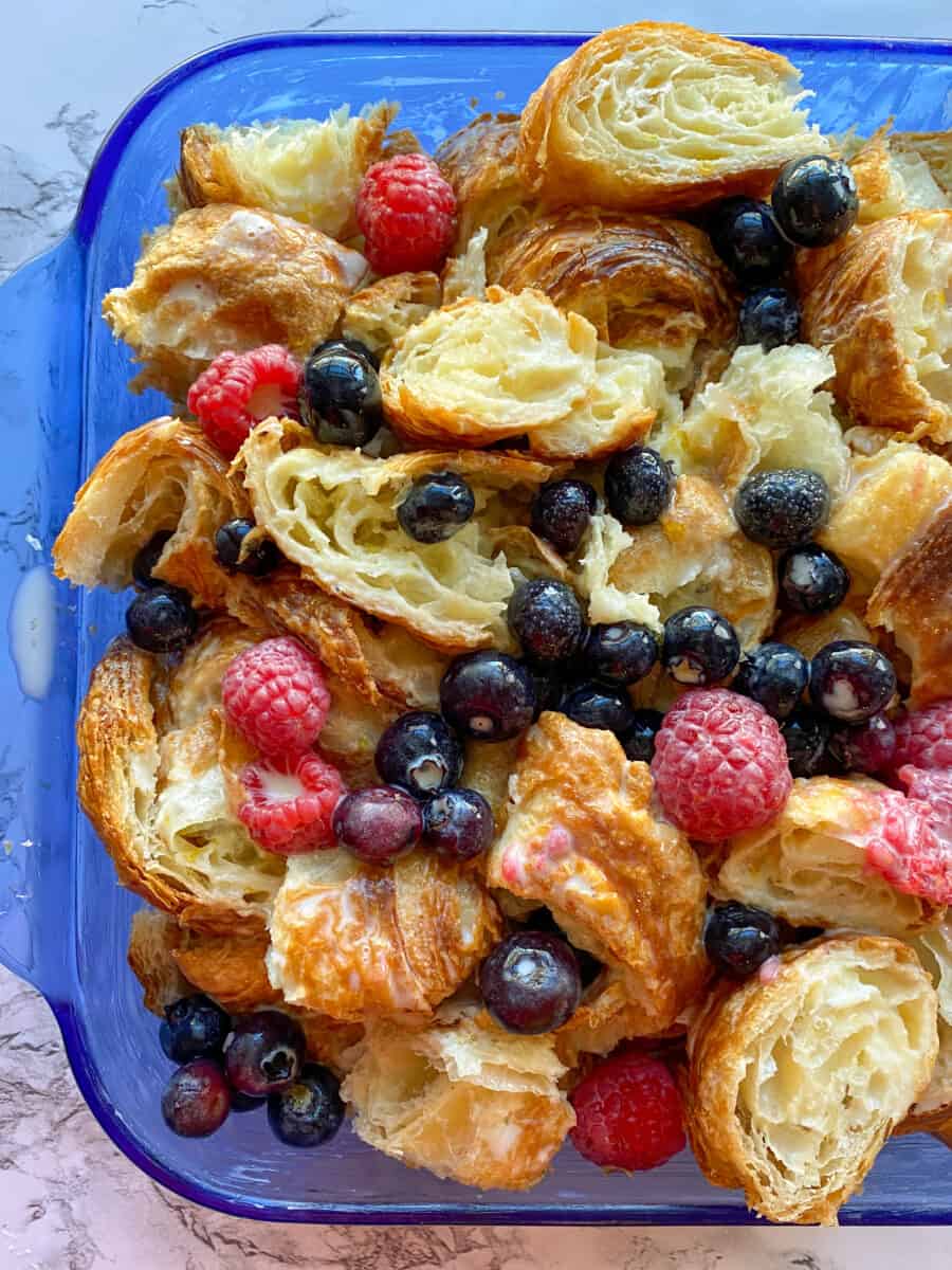 Croissants with fruit in a baking dish, before baking.