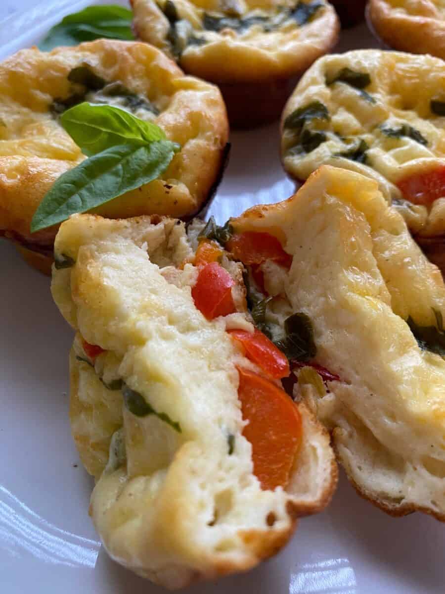 Egg bite cut in half with whole egg bites on a plate.