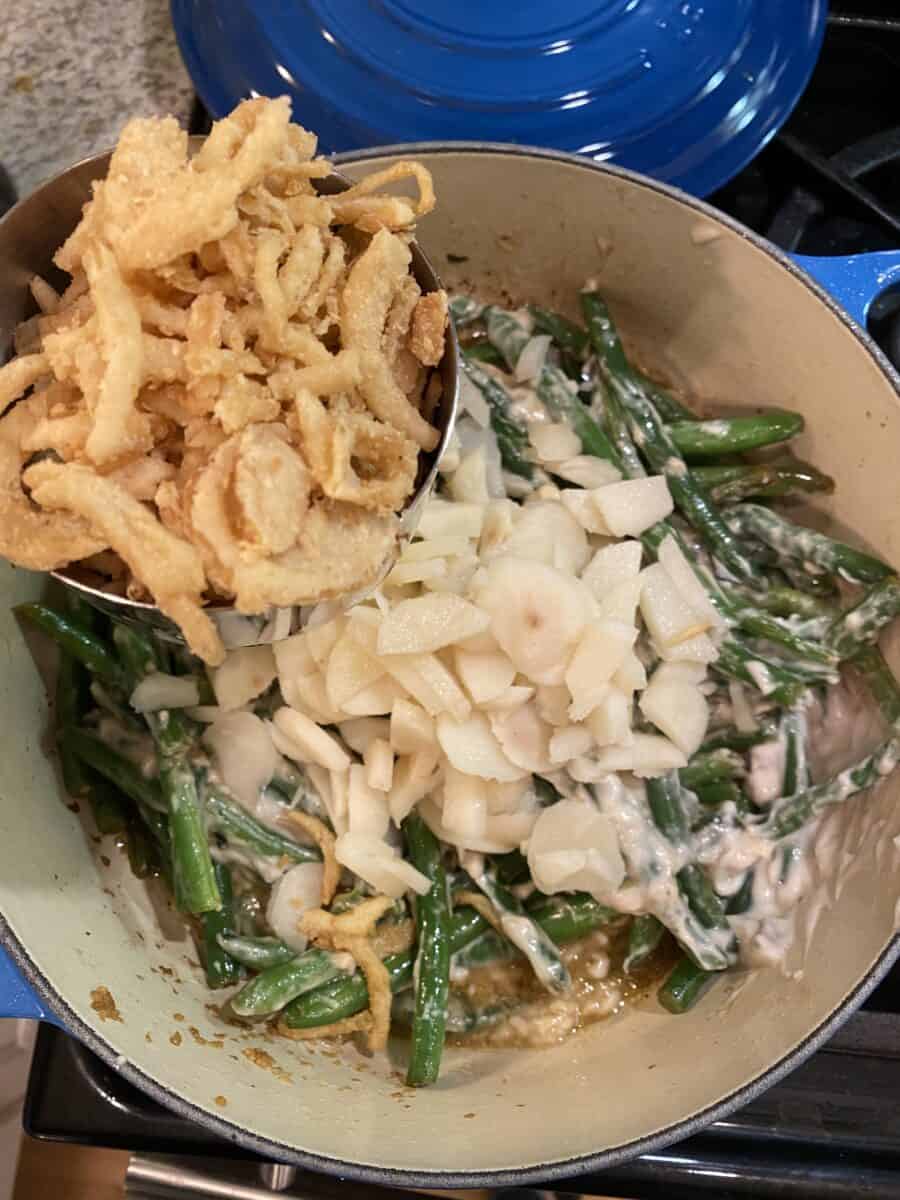 Green beans, water chestnuts and fried onions in a pan on the stove.