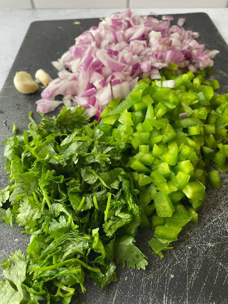 Diced onion, green pepper and cilantro on a cutting board. 