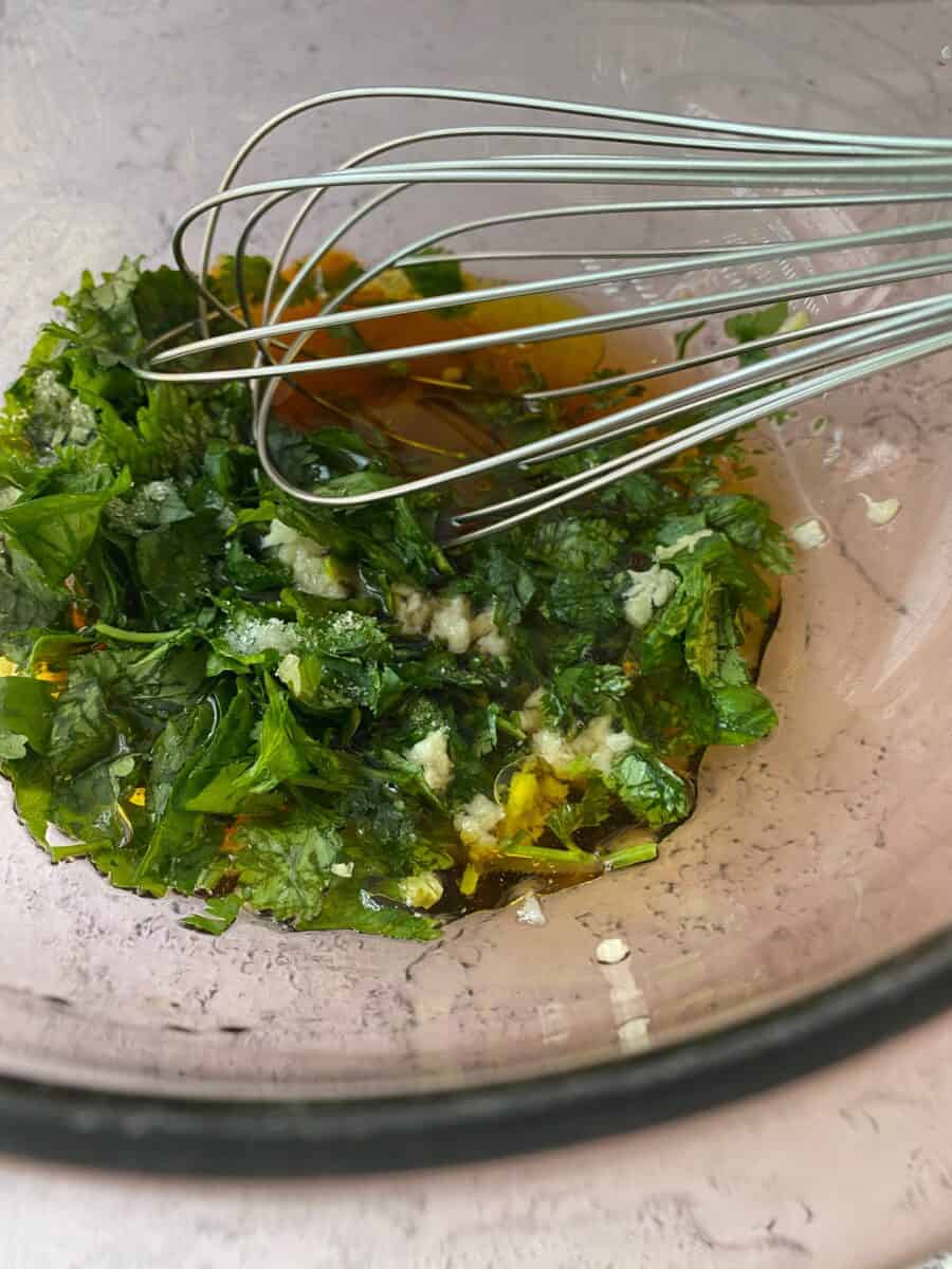 Vinaigrette ingredients in a bowl with a whisk.