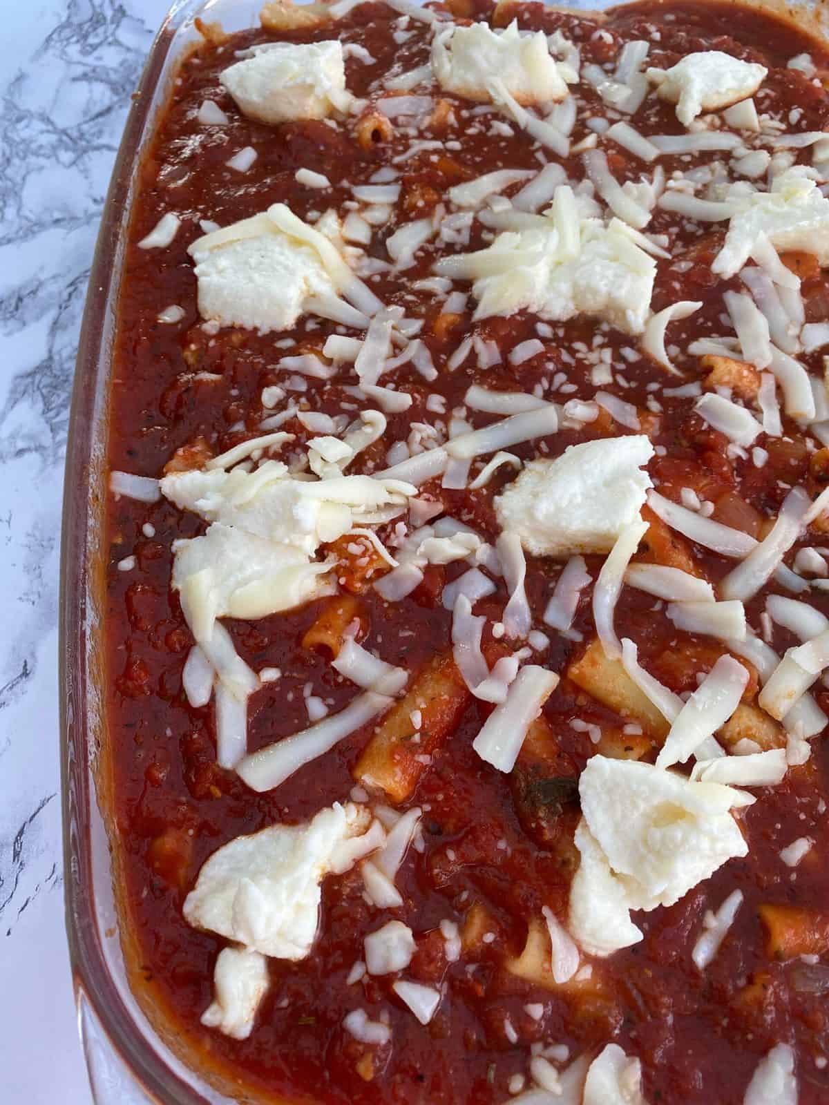 Ziti casserole with sauce on top and cheese. 